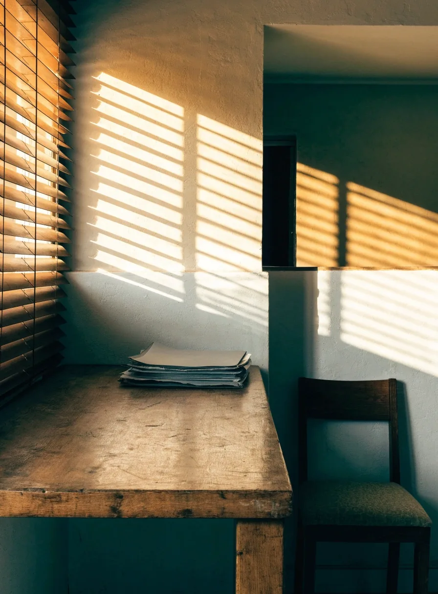 Oficina municipal con mostrador de madera y luz de tarde filtrada por una persiana