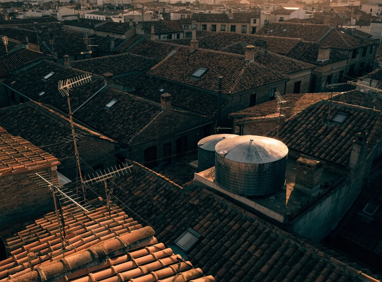 Cubiertas de Sevilla vistas desde arriba al atardecer, con tejas, antenas y depósitos de agua
